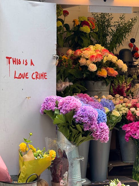 A floral display inside a flower shop featuring a variety of fresh flowers including large pink, purple, and blue hydrangeas in a clear plastic wrap, and roses in shades of pale pink and cream arrange